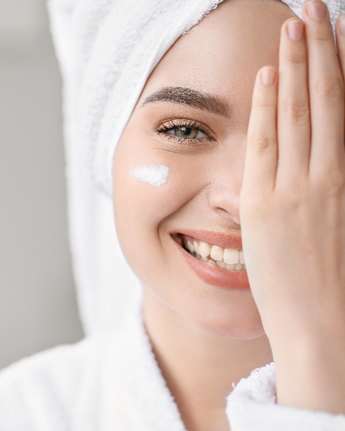Woman applying a simple morning skincare routine beside a bathroom window